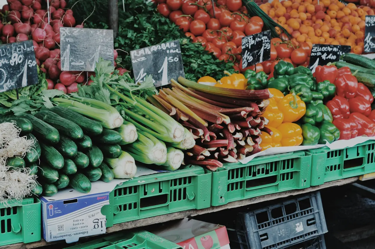 Crates of fresh cucumbers, celery, peppers and tomatoes at a produce market